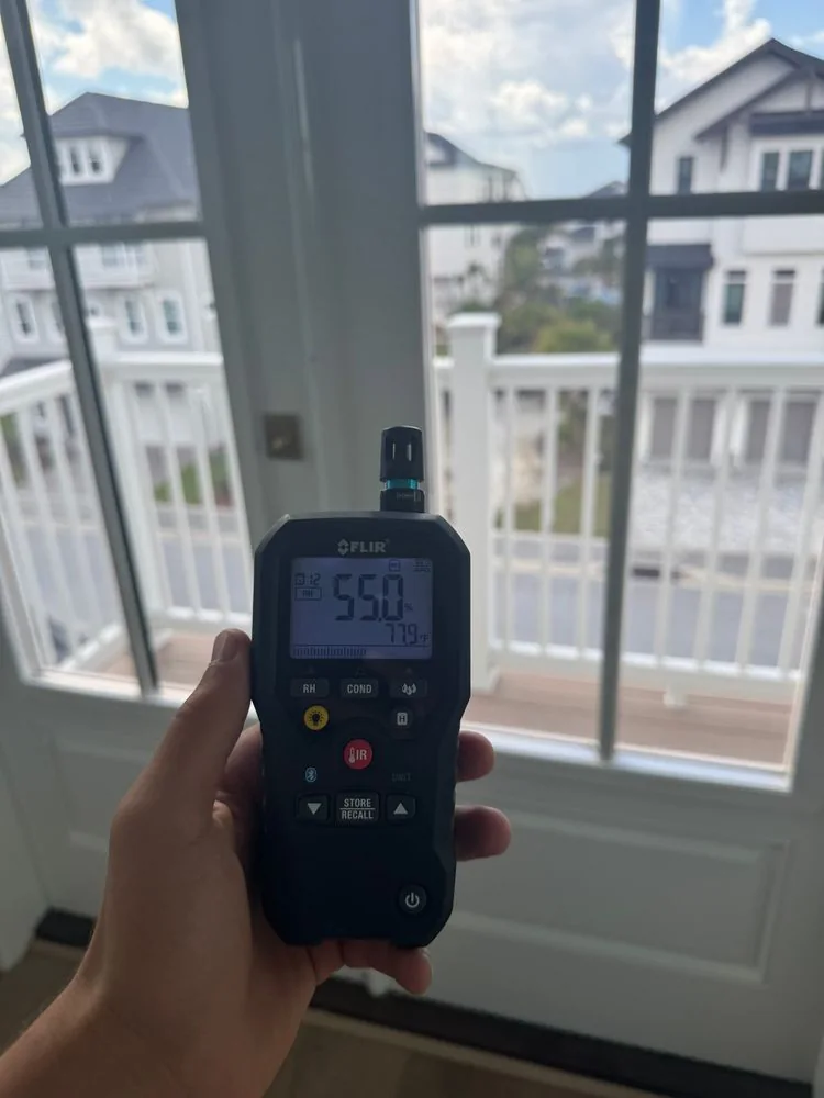 A humidity meter reading 55% at a third-floor patio door overlooking the coast
