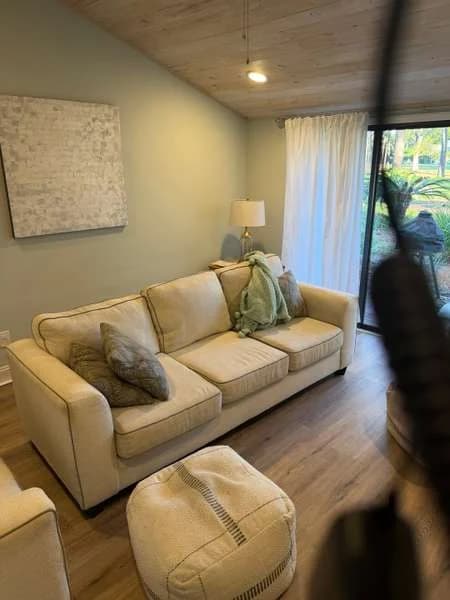 A living room with wood-look flooring and a sofa, next to the patio doors where water came in
