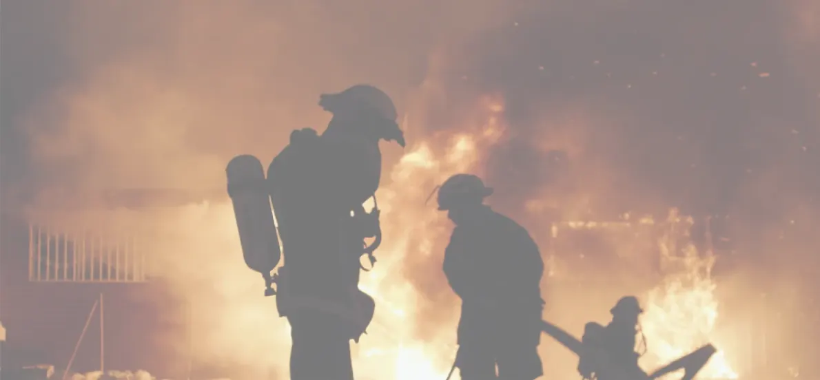 Firefighters silhouetted against a burning building