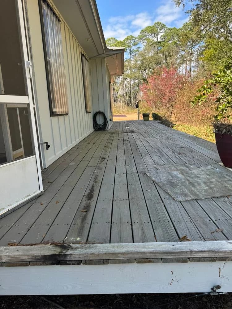 A wood deck running along the side of a house with board-and-batten siding