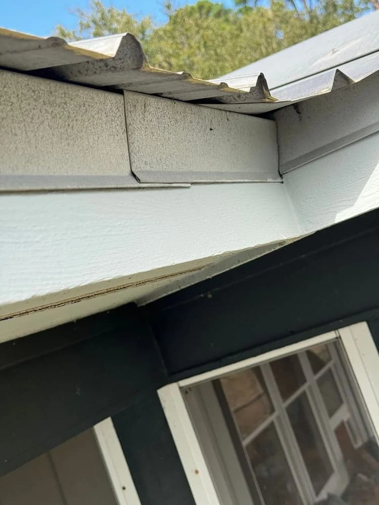 The edge of a metal roof meeting the fascia above a window