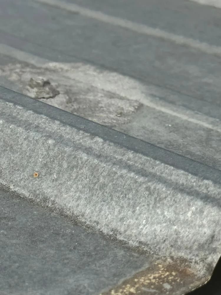 Close-up of a metal roof panel surface with worn patches