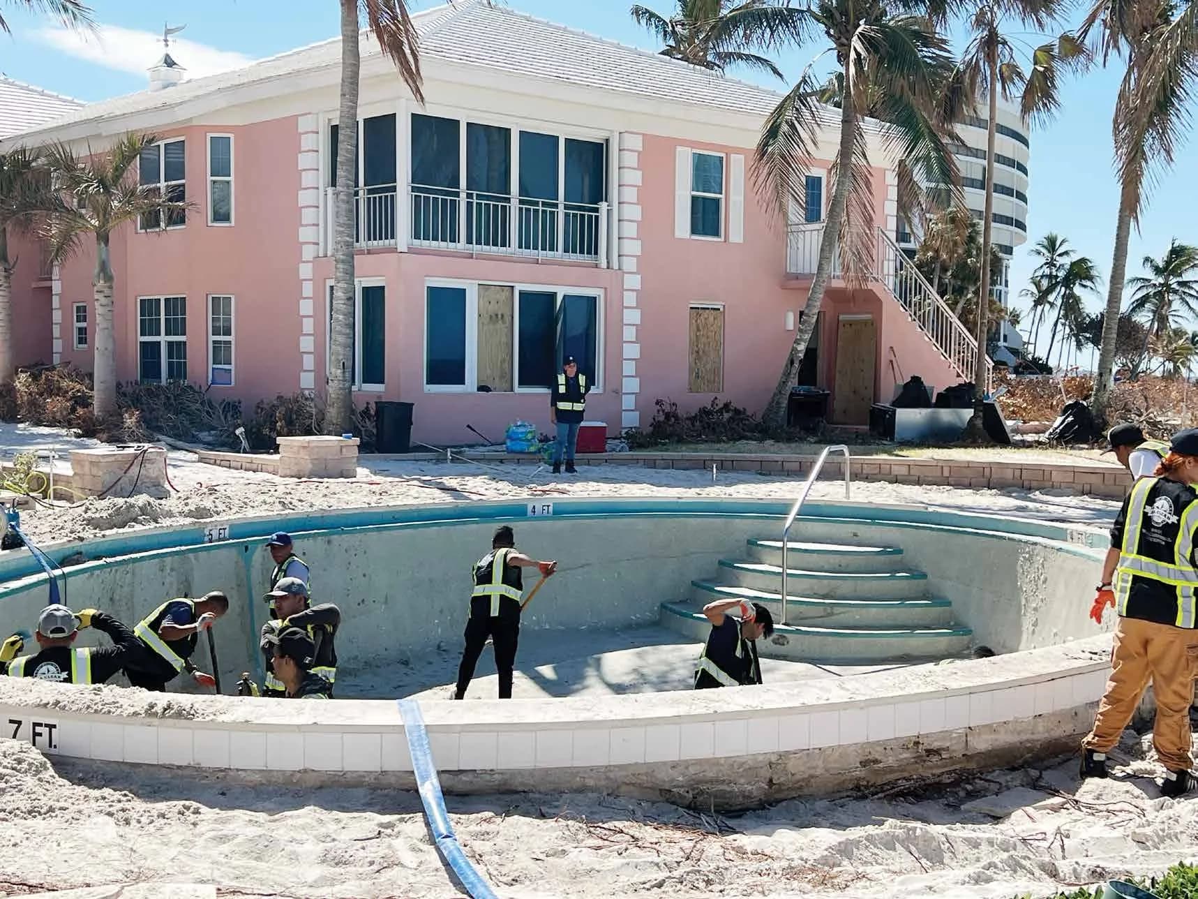 Crew clearing a hurricane-damaged resort pool